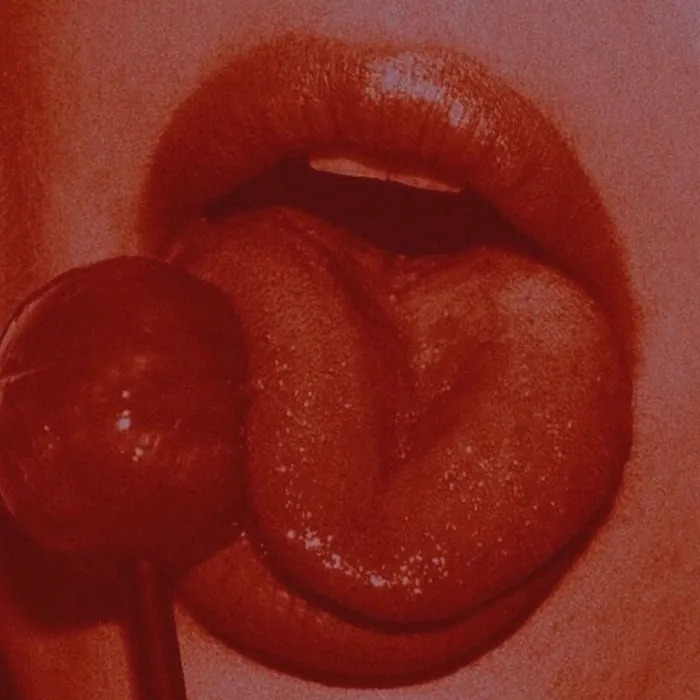 Close-up of lips around a red lollipop