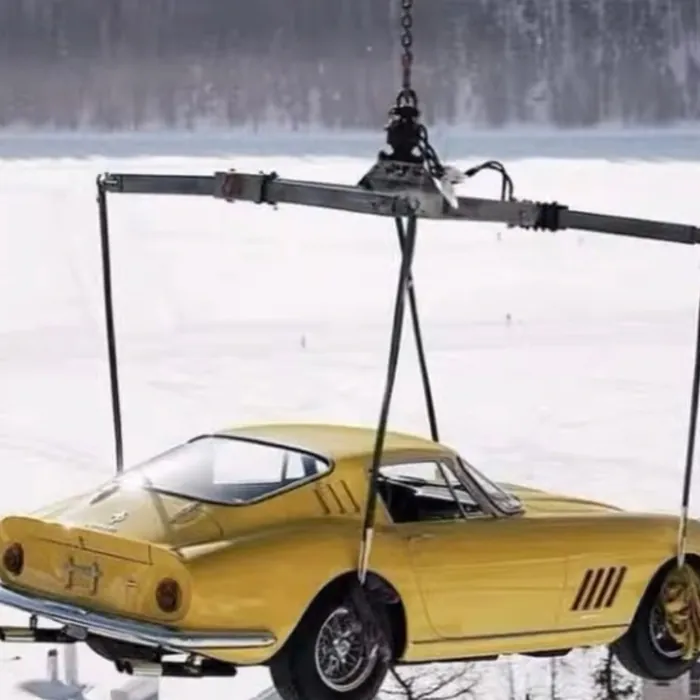 Yellow vintage sports car lifted by a crane in the snow