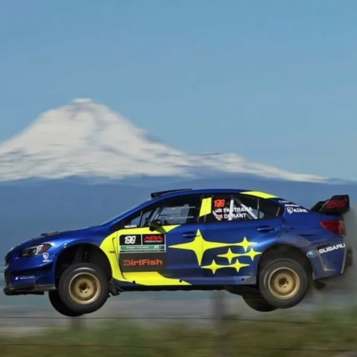 Blue rally car airborne in front of a snowy volcano
