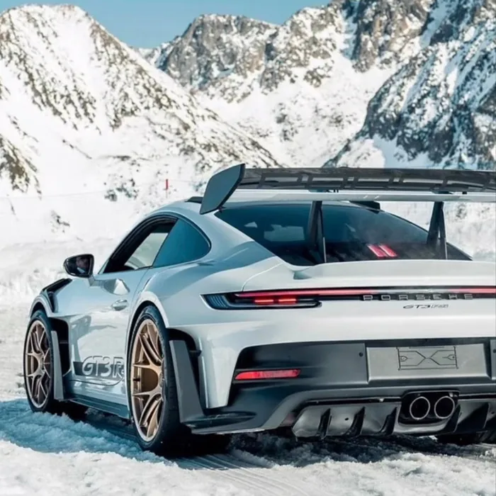 White sports car parked below snowy mountains